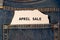 Label with text april sale in the pocket of blue denim jeans.