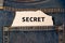 Label with text secret in the pocket of blue denim jeans.