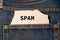 Label with text spam in the pocket of blue denim jeans.