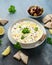 Labneh cream cheese dip with olive oil, salt, herbs served with olives, pita bread in white bowl