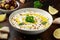 Labneh cream cheese dip with olive oil, salt, herbs served with olives, pita bread in white bowl