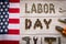 Labor day. American flag and Inscription labor day and various tools on a light wooden background