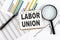 LABOR UNION text on notebook on the graph background with pen and magnifier