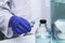 a laboratory assistant in the medical laboratory holds a syringe in his hand there are vessels of different volumes