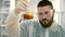 Laboratory assistant mixing red liquid in a flask