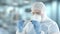 A laboratory assistant wearing protection gear examines vial with gonorrhea blood test