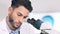 Laboratory scientist using microscope to examine monkeypox virus and note his discovery. Closeup of serious biochemist
