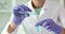 Laboratory worker holds glass test tube pouring blue liquid