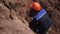 Laborer grinds yellow pipe casing sitting inside trench