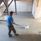 Laborer polishing sand and cement screed floor.