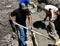 Laborers moving wet concrete on a building project as footings are created.