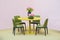 Laconic interior of the dining room. Yellow round table and green leather chairs, vase with flowers on the table. Isolate on pink