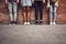 Laconic photo of four pairs of legs by the brick wall