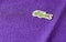 The Lacoste logo sewn onto a purple polo shirt