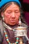 Ladakhi women with hand prayer wheels in traditional clothes and jewelry prays with eyes closed on buddhist festival in Lamayuru