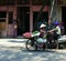 Ladies chatting in doorway whilst man on motorcycle and lady on pushbike go past, Hanoi Vietnam