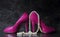 Ladies pink high heels with long strand of white pears against a