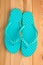 Ladies turquoise flip flops on the wooden floor