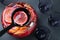 Ladle with aromatic punch drink above glass bowl on black table, top view