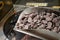 A ladle with pieces of raw chocolate in the hands of a pastry chef against the background of a production line, small-scale