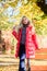 Lady attractive posing in jacket near bench. Woman fashionable blonde with makeup stand in autumnal park. Jacket for