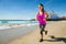 Lady on beach blue skies run jog fitness athlete weight training endurance runner pier ocean