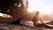 Lady and black dog sit on sandy beach under bright sun rays