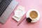 Lady blogger's home workplace, cup of coffee and laptop keyboard on pink tabletop