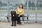 Lady and briard are waiting for bus on public transport stop.