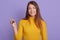 Lady with charming smile standing against lilac wall, girl holding car key, female with long beautiful hair wearing yellow casual