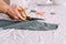 Lady cuts with scissors from a piece of fabric in front of a sewing tool