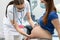 A lady doctor checks the abdomen of a pregnant patient with her hands. Protective masks placed over the mouth and nose