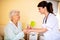 Lady doctor handing a glass of water to elder woman nursing home occupant