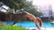 Lady does legged downward-facing dog yoga positions by pool