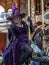 Lady dressed up as a witch in purple garment riding on the carousel