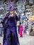 Lady dressed up as a witch in purple garment on the street