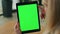 Lady finger swiping greenscreen tablet at office. Anonymous woman surfing web