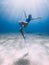 Lady freediver with fins posing and glides underwater in sea with sunlight. Freediving in warm water
