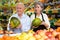 Lady greengrocer worker helping old man to choose melon