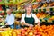 Lady greengrocer worker and old man customer in salesroom