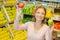 Lady in grocers holding two apples different varieties