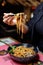 Lady hand with chopsticks. Female hand with chopsticks takes noodles and eats