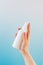 Lady hand sprays air refresher from blank bottle on blue background close view