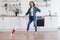 Lady in headphones dusting off floor with stick vacuum