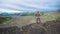 Lady hiker with backpack standing on top of the mountain, view from volcano peak to frozen lava valley