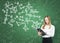 Lady is holding a black document folder and a range of math formulas are drawn on the green chalkboard.