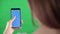 Lady holds the phone hand and scrolls finger down chromakey phone screen to track and insert video