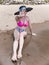 A lady in a large sun hat and bikini declines to have her photo taken at the beach, preferring to go incognito and not have