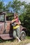 Lady leaning against vintage car playing her harp