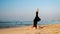 Lady lies on yellow sandy beach lit by sun in yoga pose